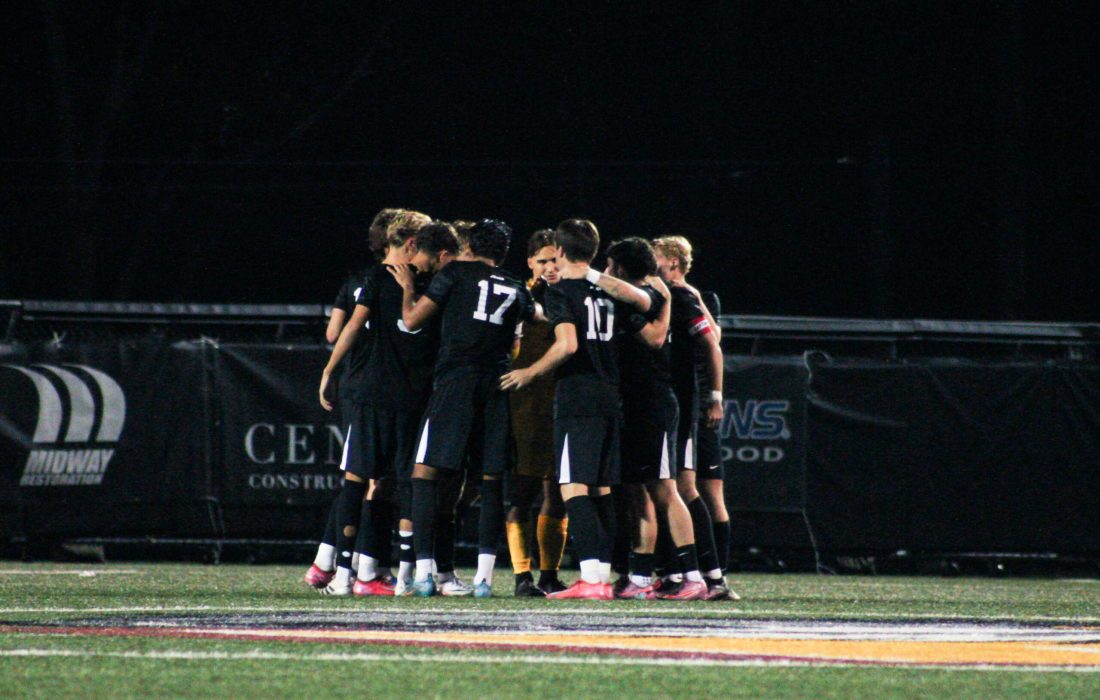 Men's soccer huddles before their match against La Salle University. (Bella Adams | The Phoenix)