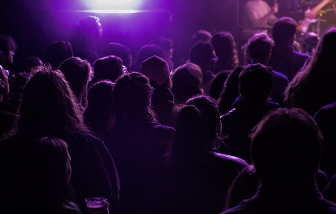 Attendees dance at a concert under purple lighting. (Bella Adams | The Phoenix)
