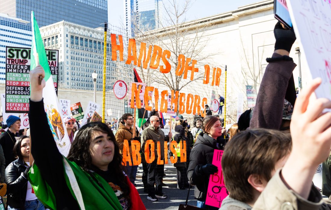 Protestors carry a sign reading "HANDS OFF OUR NEIGHBORS, ABOLISH ICE" (Kayla Tanada / The Phoenix)