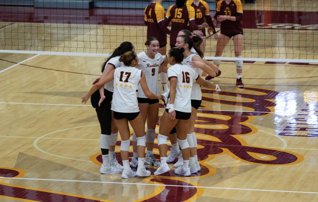 The Ramblers huddle after a set point during the match against Minnesota. (Megan Dunn | The Phoenix)